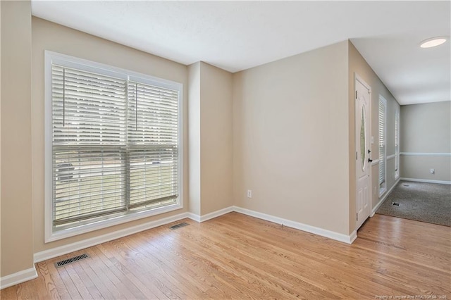 spare room featuring baseboards, light wood-type flooring, and visible vents
