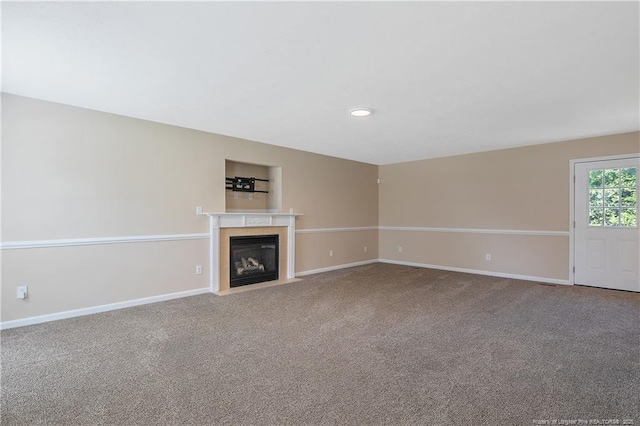 unfurnished living room with a fireplace with flush hearth, built in shelves, baseboards, carpet flooring, and recessed lighting