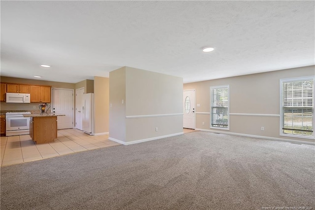 unfurnished living room with recessed lighting, baseboards, and light carpet