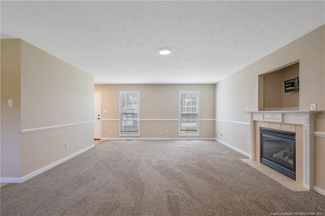 unfurnished living room with light colored carpet, baseboards, and a tile fireplace
