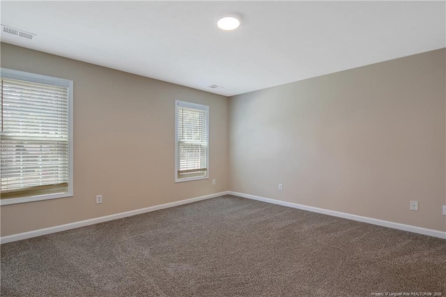 spare room featuring baseboards, visible vents, and carpet