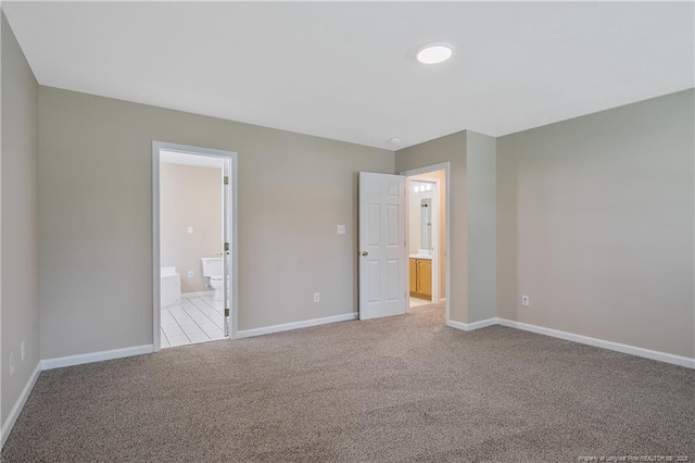 unfurnished bedroom featuring baseboards, carpet, and ensuite bath