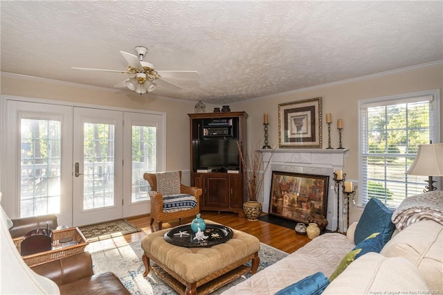 living area featuring a textured ceiling, a ceiling fan, wood finished floors, a high end fireplace, and ornamental molding
