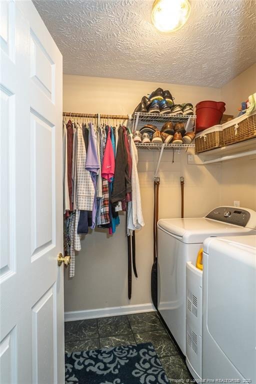 washroom with baseboards, laundry area, a textured ceiling, and washer and clothes dryer