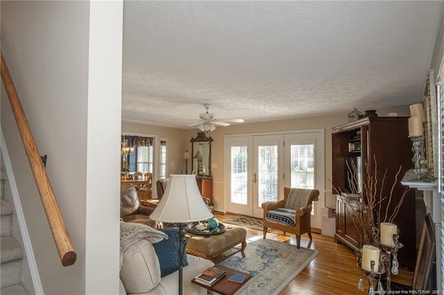 living room with french doors, a textured ceiling, wood finished floors, and stairway
