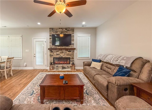 living area with baseboards, ceiling fan, wood finished floors, and a fireplace