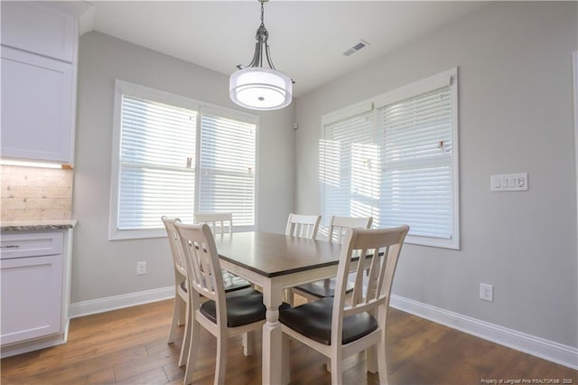 dining area featuring baseboards, visible vents, a healthy amount of sunlight, and dark wood-type flooring