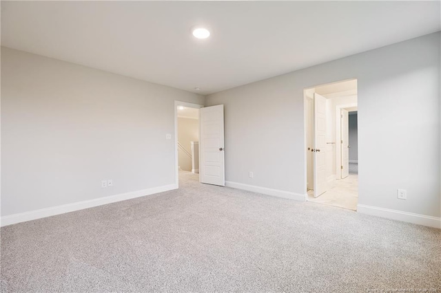 empty room featuring light colored carpet, recessed lighting, and baseboards