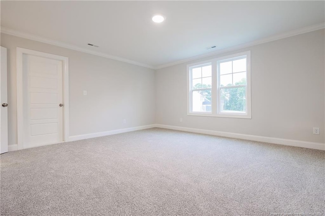 spare room featuring crown molding, baseboards, and light colored carpet
