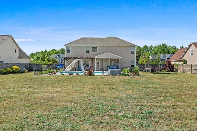6628 Carriage Crossing Rd, Hope Mills, NC 28348 - rear view of property featuring a lawn, a fenced backyard, a trampoline, and a fenced in pool