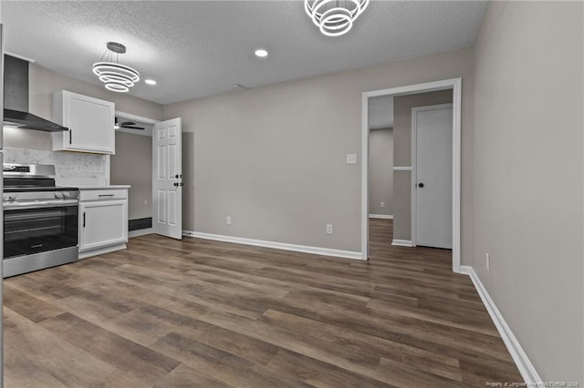 kitchen with a textured ceiling, wall chimney exhaust hood, white cabinetry, dark wood finished floors, and stainless steel range with electric cooktop