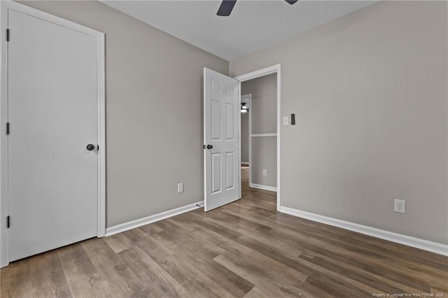 unfurnished bedroom featuring a ceiling fan, baseboards, and wood finished floors
