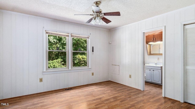 3899 Warrenton Rd, Henderson, NC 27537 - unfurnished bedroom featuring wood finished floors, a textured ceiling, crown molding, ensuite bathroom, and wood walls