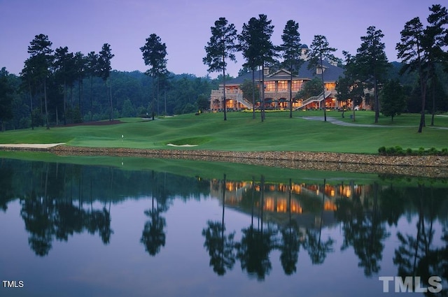 surrounding community featuring a water view, a yard, view of golf course, and an area to practice putting