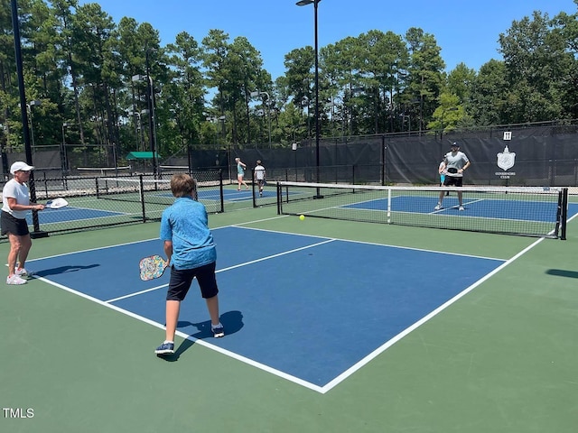 view of tennis court featuring community basketball court and fence