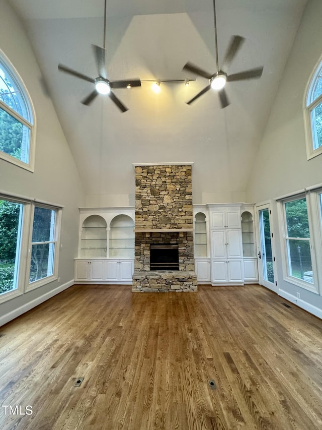 90021 Hoey, Chapel Hill, NC 27517 - unfurnished living room featuring a ceiling fan, high vaulted ceiling, a stone fireplace, wood finished floors, and baseboards