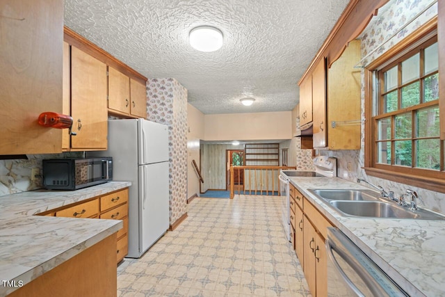 kitchen with a sink, light countertops, light floors, under cabinet range hood, and white appliances