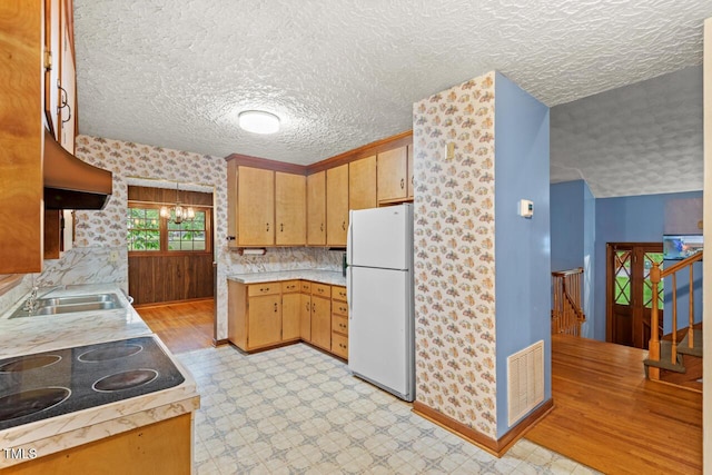 kitchen with light countertops, extractor fan, freestanding refrigerator, baseboards, and visible vents
