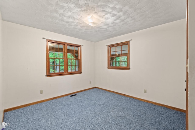 empty room featuring a healthy amount of sunlight, carpet flooring, a textured ceiling, and visible vents