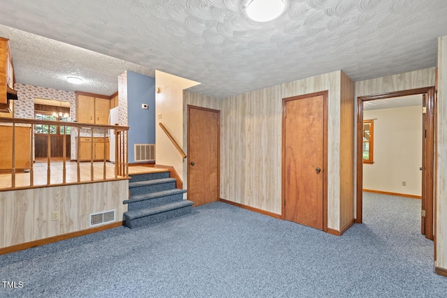 unfurnished living room with baseboards, stairs, and visible vents