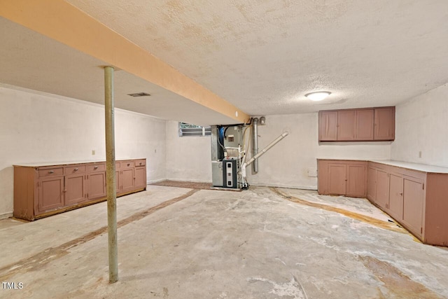 finished basement featuring heating unit, a textured ceiling, and visible vents