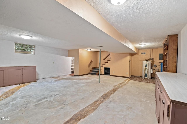 basement with stairway, water heater, a textured ceiling, and visible vents