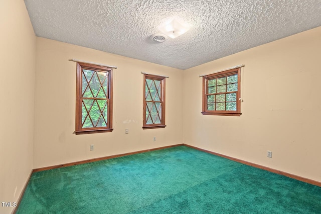 empty room featuring carpet floors, a textured ceiling, baseboards, and visible vents