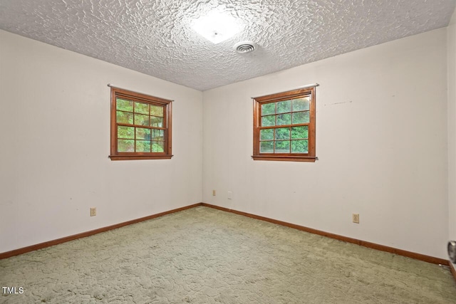 spare room featuring baseboards, carpet, a textured ceiling, and visible vents