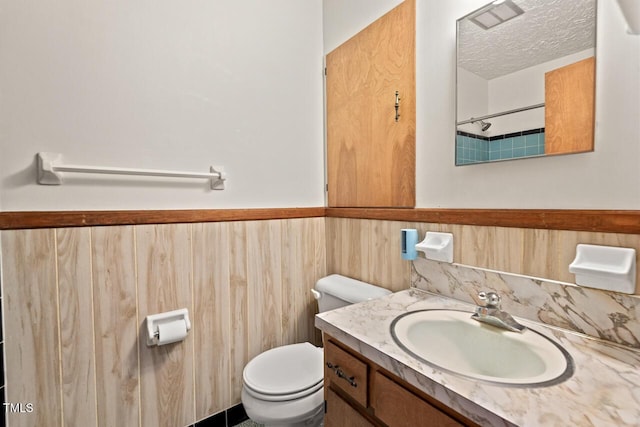 bathroom with visible vents, a wainscoted wall, vanity, toilet, and wooden walls