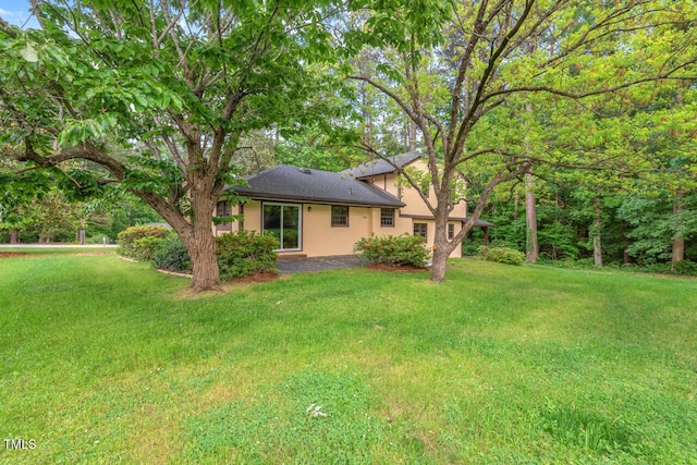 rear view of property with stucco siding and a yard