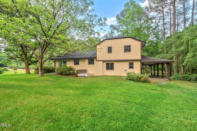 rear view of house featuring a yard, stucco siding, and an attached carport