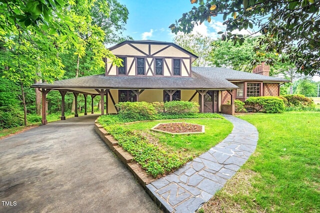 view of front of house with aphalt driveway, a front yard, stucco siding, a chimney, and a shingled roof