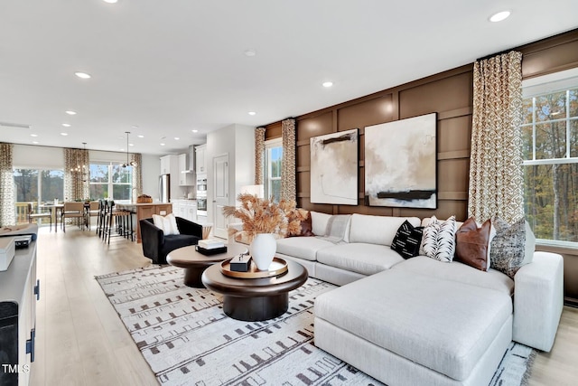 living room with recessed lighting, a notable chandelier, and light wood-type flooring