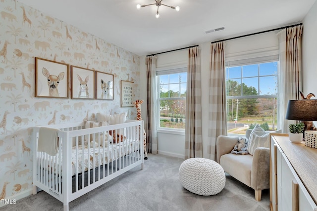 bedroom featuring light colored carpet, visible vents, a nursery area, baseboards, and wallpapered walls