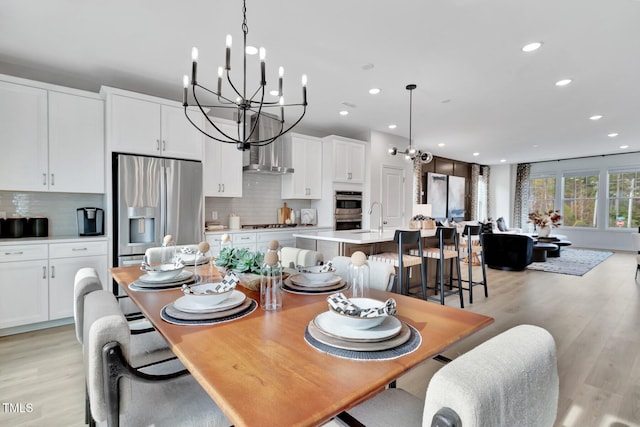 dining area with light wood-type flooring, recessed lighting, and a chandelier