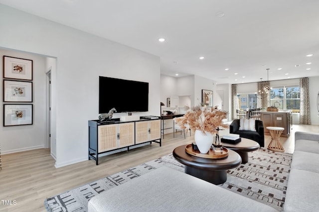living room with light wood-style floors, baseboards, recessed lighting, and a chandelier