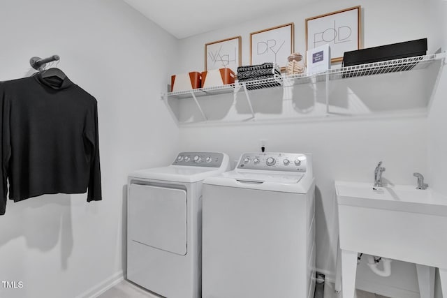 clothes washing area with independent washer and dryer, laundry area, and a sink