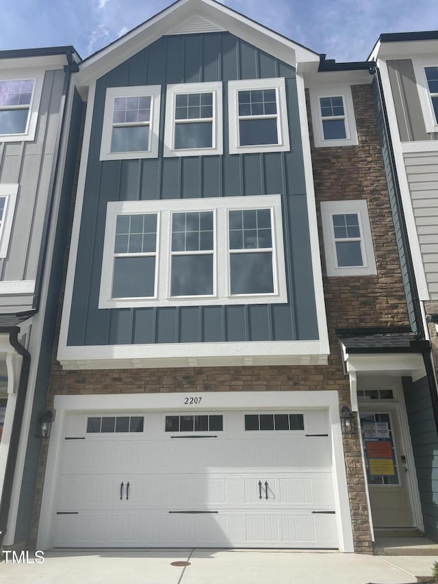 view of front of house with concrete driveway, board and batten siding, an attached garage, and stone siding