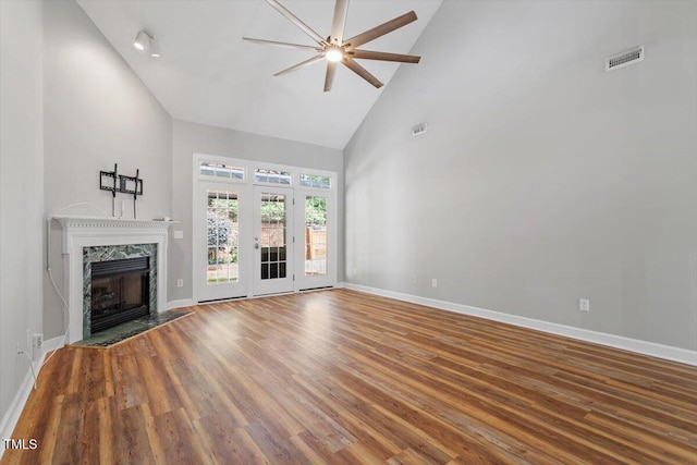 unfurnished living room with ceiling fan, wood finished floors, high vaulted ceiling, baseboards, and a premium fireplace