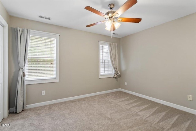 carpeted spare room with a ceiling fan, baseboards, and visible vents