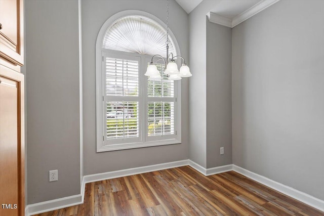 unfurnished dining area with crown molding, baseboards, wood finished floors, and a notable chandelier