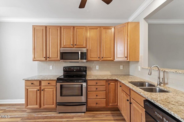 kitchen featuring a sink, appliances with stainless steel finishes, ornamental molding, and light stone counters