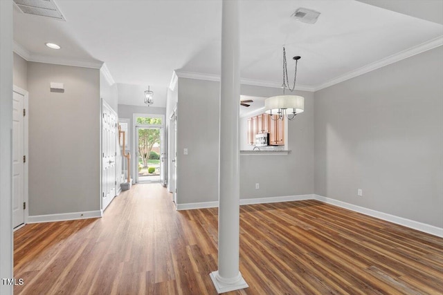 foyer with crown molding, baseboards, wood finished floors, and visible vents