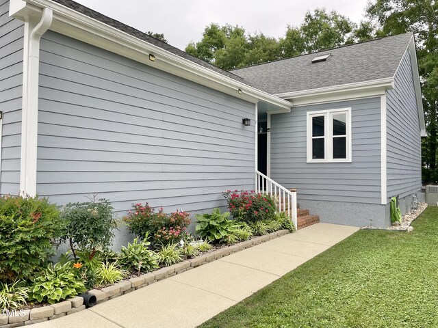 1944 Castle Pines Dr, Raleigh, NC 27604 - view of front of home with a front yard, a shingled roof, and central AC