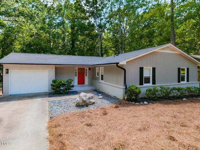 single story home featuring an attached garage, a shingled roof, driveway, and brick siding