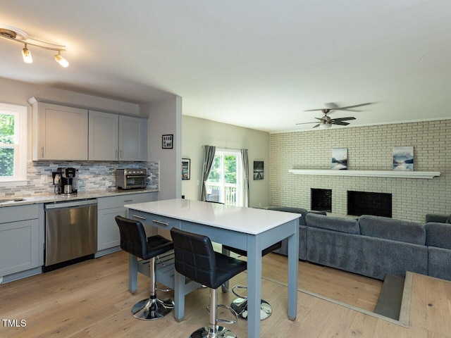 kitchen featuring decorative backsplash, gray cabinets, ceiling fan, dishwasher, and light wood-style floors