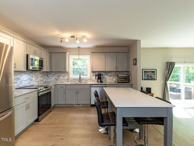 kitchen featuring a sink, gray cabinetry, backsplash, and stainless steel appliances