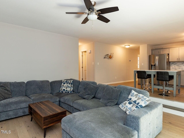 living room with a ceiling fan and light wood finished floors