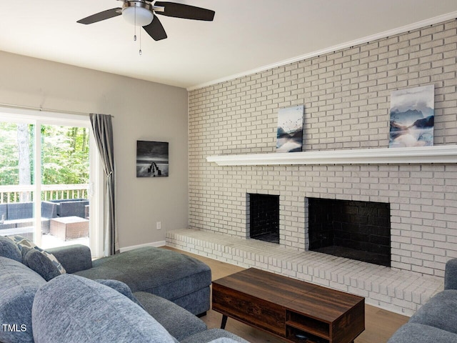 living area with a ceiling fan, a brick fireplace, and wood finished floors