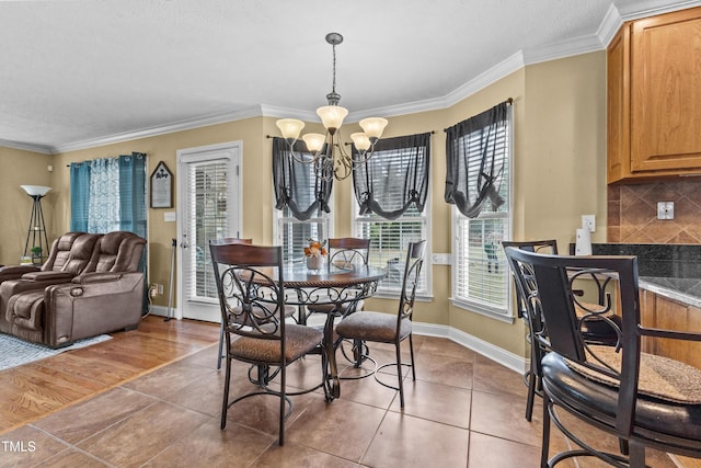 tiled dining area with crown molding, baseboards, and a chandelier